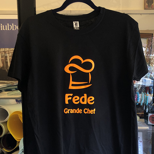 Maglietta nera con cappello da chef arancione e la scritta Fede Grande Chef