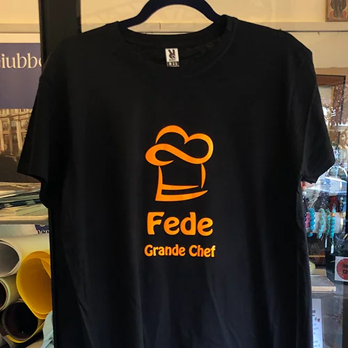 Maglietta nera con cappello da chef arancione e la scritta Fede Grande Chef