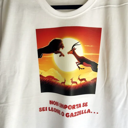Maglietta bianca con illustrazione di leone e gazzella al tramonto e frase in rosso
